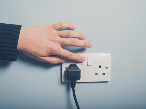 A wall plug being turned on
