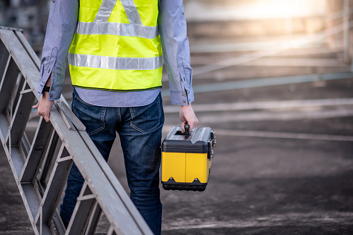 Man in high vis holding ladder