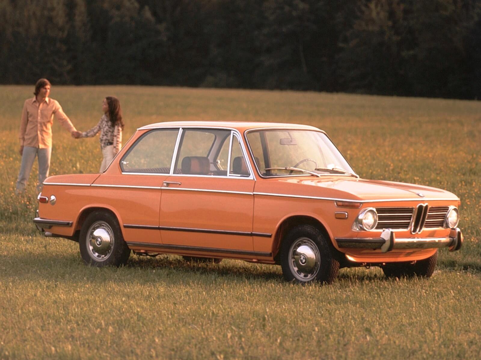 A BMW 2002 parked in an idyllic country field