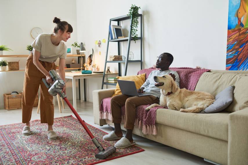 Image of a couple with a dog vacuuming.