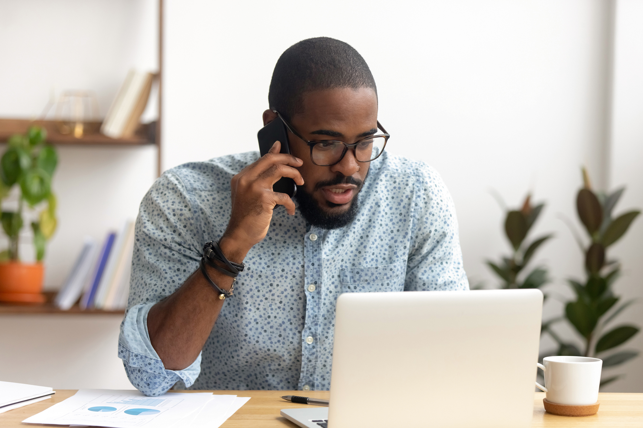 man at laptop speaking on phone