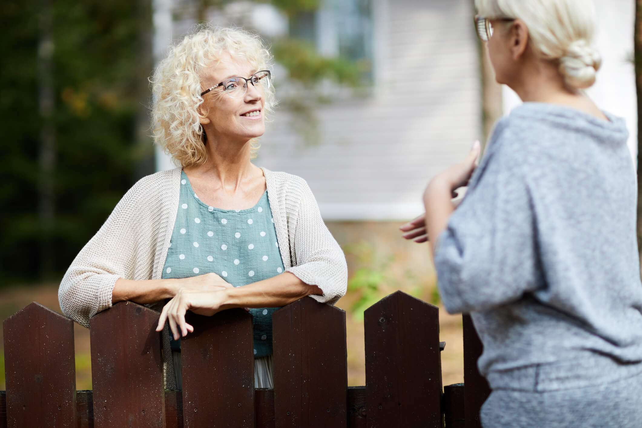 two middle aged women chatting over the fence
