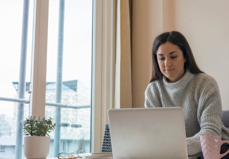 woman sitting on a sofa with her laptop in her apartment.