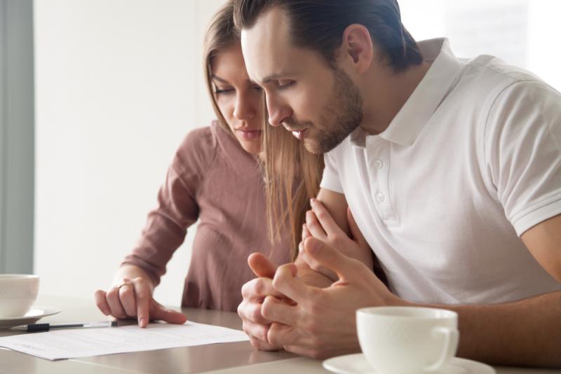 couple-sat-at-a-table-looking-at-loan-documents