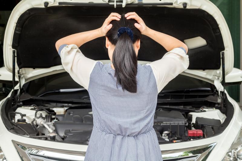a-woman-standing-in-front-of-her-broken-down-car