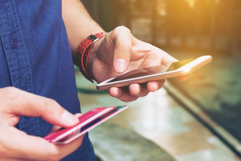 man-using-smartphone-holding-credit-card