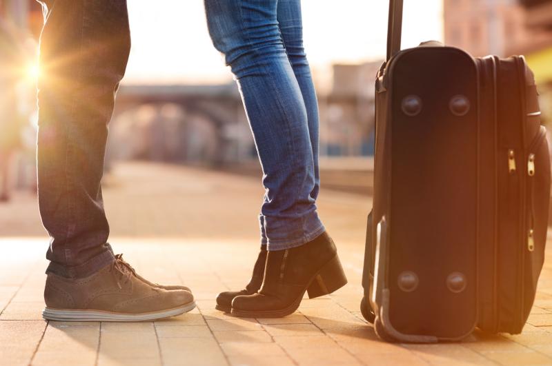 close-up-of-feet-standing-by-a-suitcase