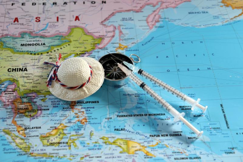 Two travel vaccination syringes on top of a world map