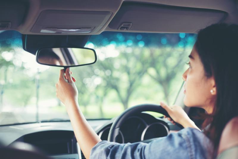 young-woman-driver-adjusting-mirror