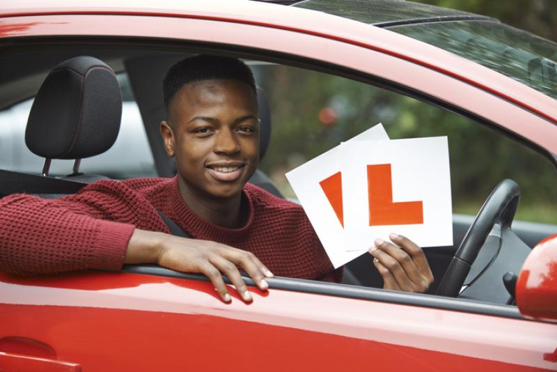 teenage-boy-in-car-holding-l-plates