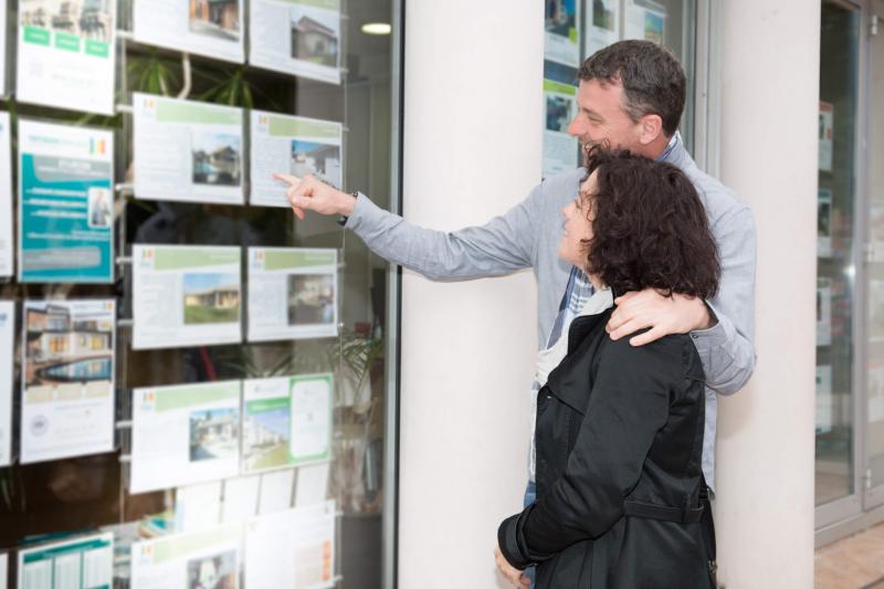 couple looking at houses in estate agent window