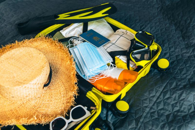 packed suitcase with passport and face masks