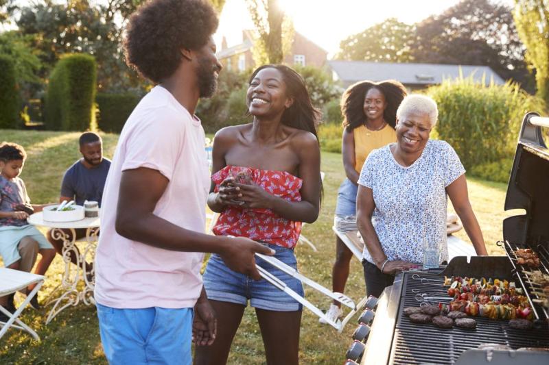 family gathered around bbq cooking food