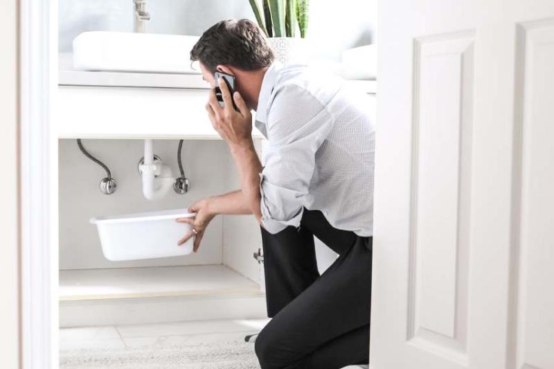 Image of a white man calling for help after spotting a house leak