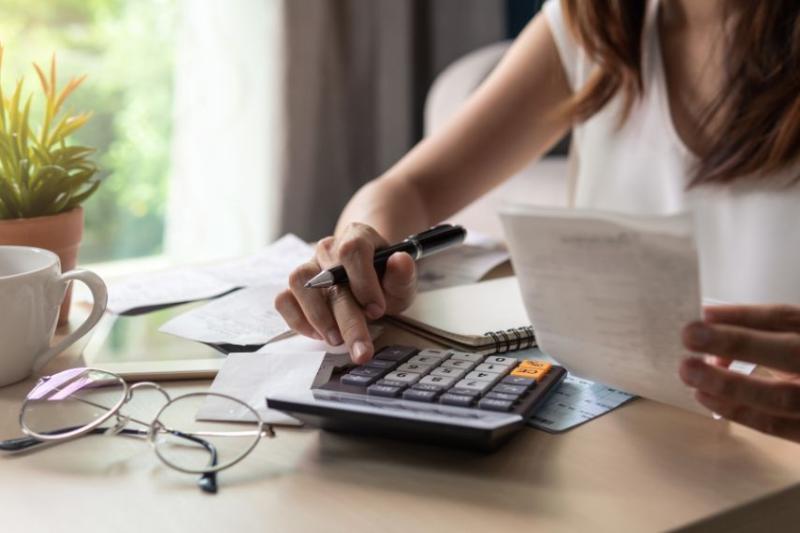 Woman sat at table budgeting with a calculator