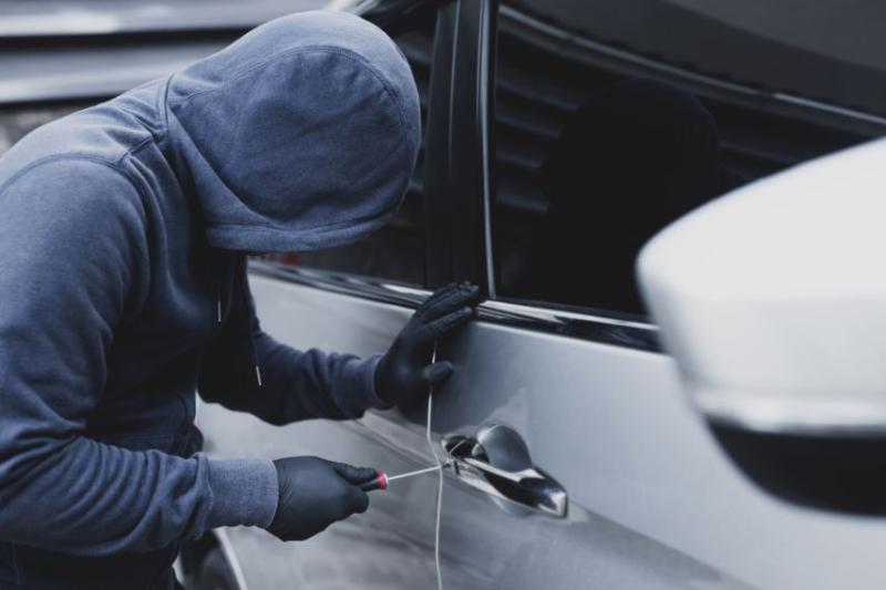 Person in mask and gloves breaking into car