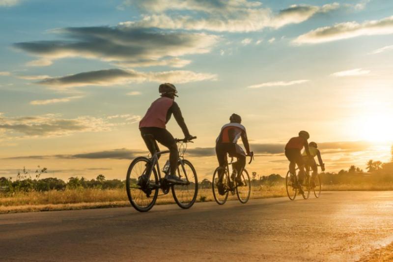 Four people on riding bicycles at sunset