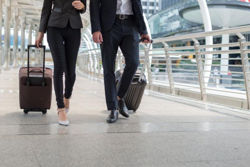 A businessman and businesswoman wheeling suitcases