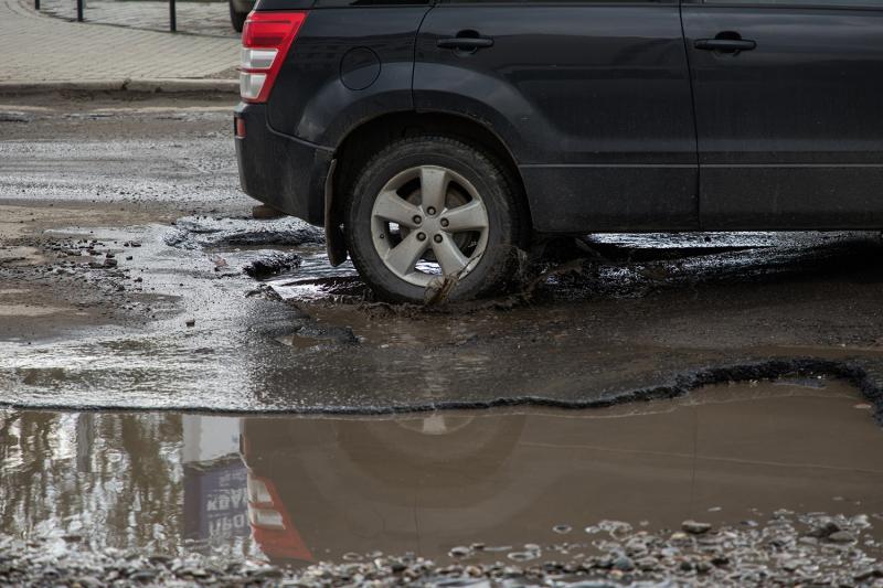 Car driving through water filled pothole