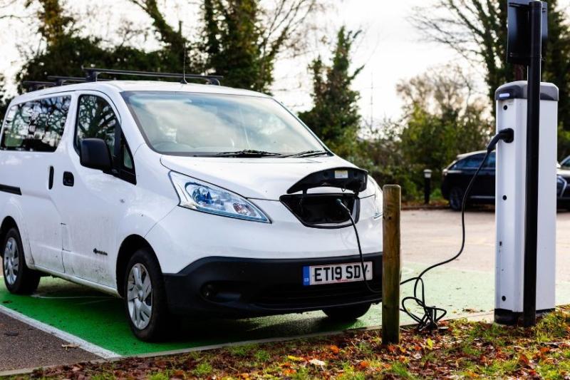 white electric van charging at station outside