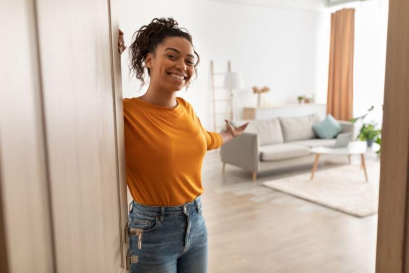 Woman in orange jumper opening the door to her apartment