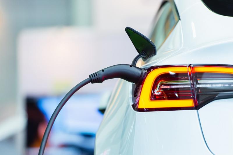 White electric car viewed from rear getting charged at electric charge point