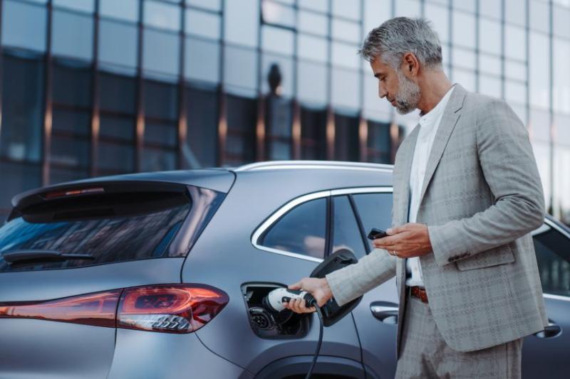 A man in a grey suit charging his EV