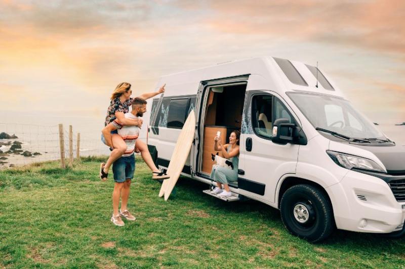 A man giving a woman piggyback in front of a van