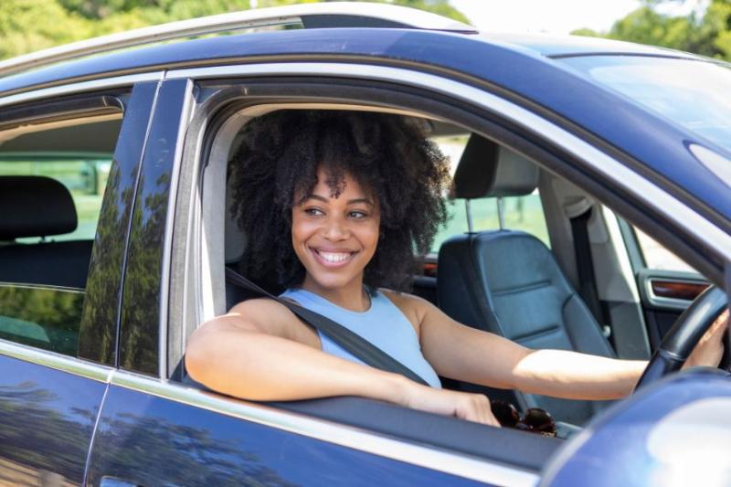 A woman in blue top driving in car