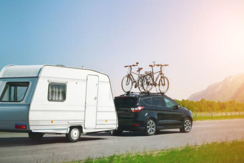 A car with two bikes secured on top towing a caravan