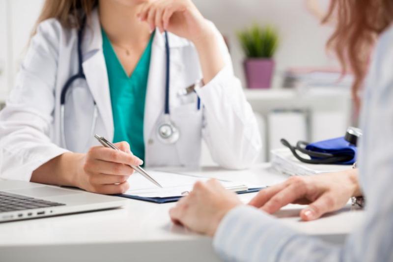 A doctor with a clipboard, speaking to a patient