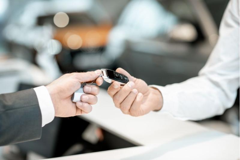 Someone handing a car key to someone else, just their hands