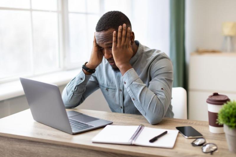 A man at a laptop with his head in his hands looking stressed