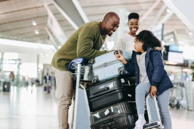 A mother and father in the airport with their daughter, with a trolley of suitcases