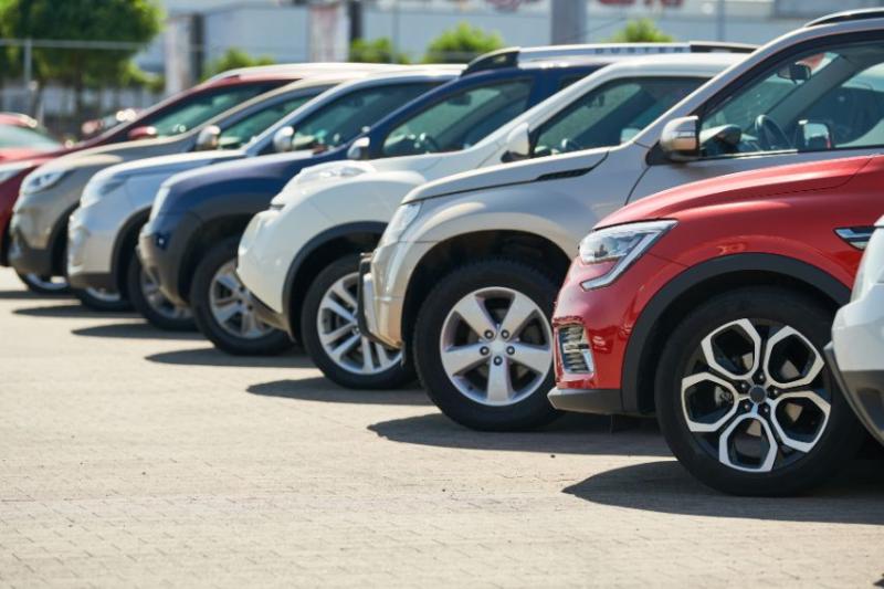 A line of cars next to each other, one red one at the forefront