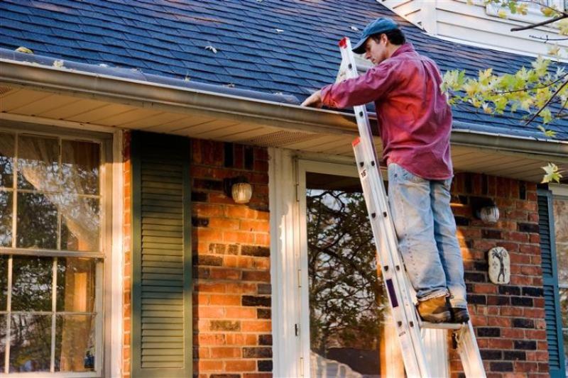 Man in a red shirt clearing a gutter