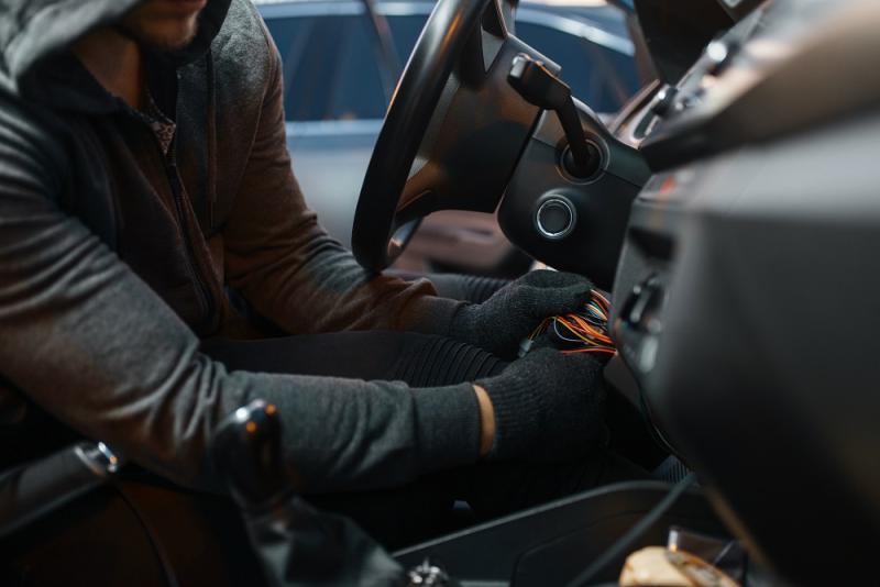 Professional car thief hacking ignition lock steering wheel