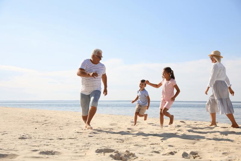 Children with grandparents spending time together on sea beach By New Africa