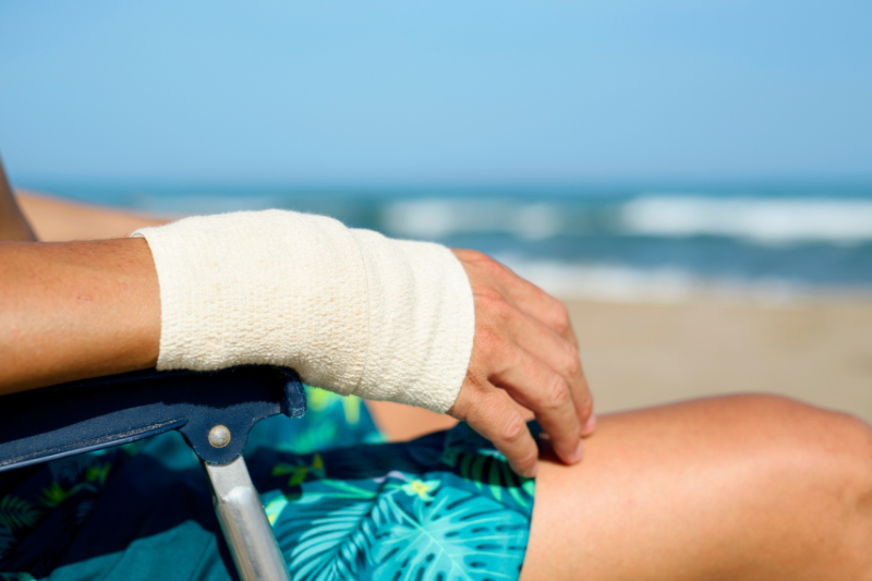 person with bandaged arm on beach