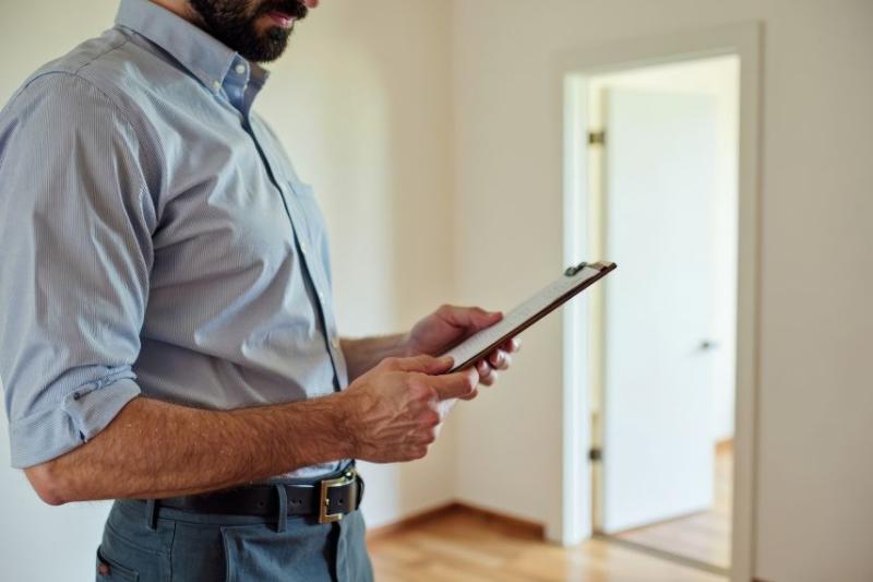 Man with clipboard inspects a property