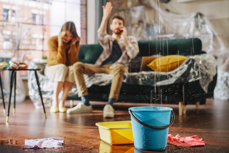 couple on phone while ceiling leaks in house