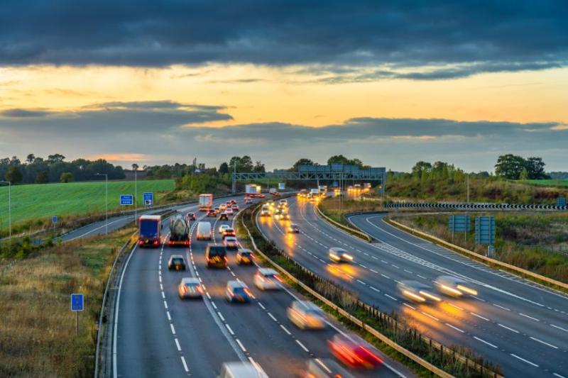 Cars driving down a UK motorway at sunset
