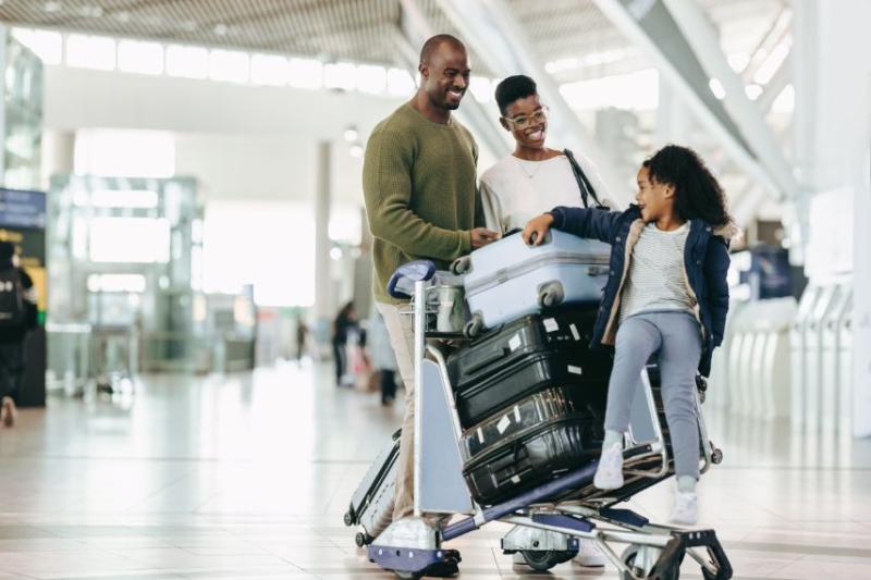 A couple at the airport with their child and luggage on a trolley