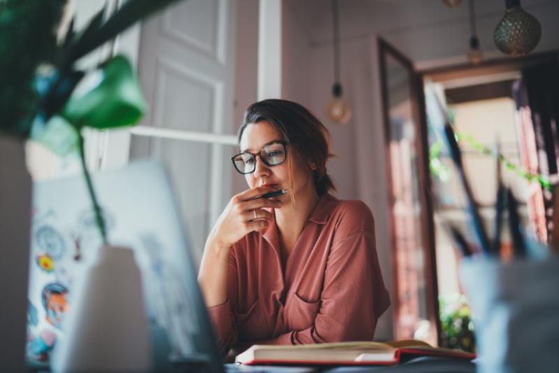 A woman wearing glasses looking at her laptop in her house