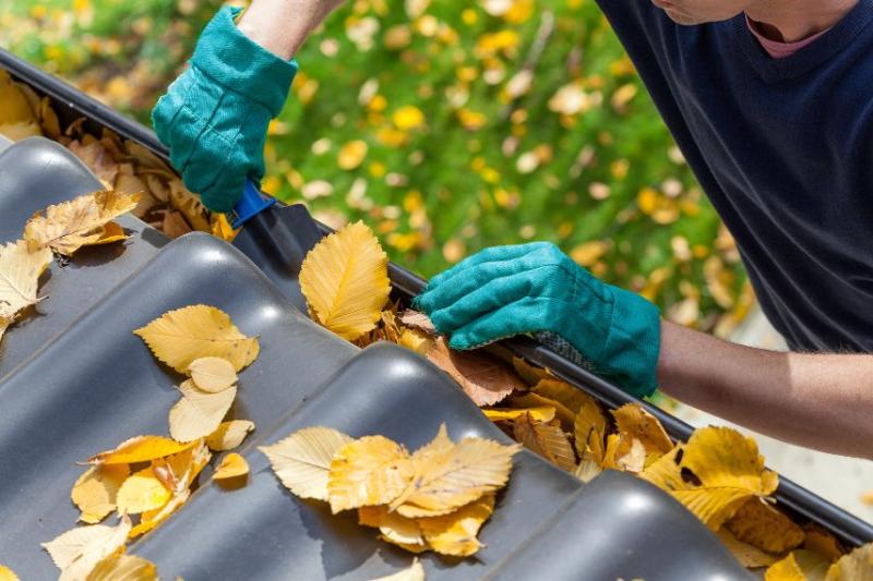 A man with teal gloves clearing out the gutters