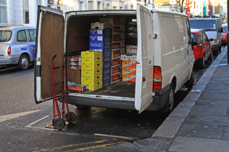 A white van parked on a street with the back doors open to see stock inside