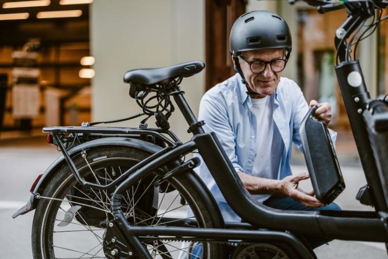 A middle-aged man wearing a helmet checking his electric bike