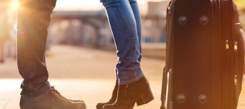 close-up-of-feet-standing-by-a-suitcase