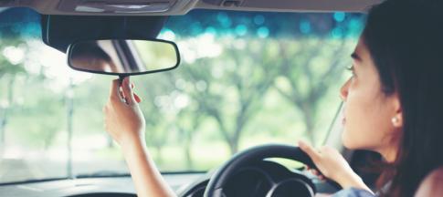 young-woman-driver-adjusting-mirror
