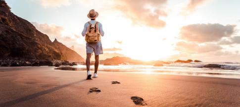 man walking on a beach with a backpack on 